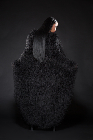 Beautiful watch lady in black clothes showing her back over dark background.の写真素材