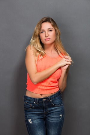 Portrait of beautiful hipster blonde posing with her hands clasped in photo studio.