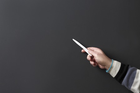 Closeup image of professor man's hand holding pen while explaining new material to students or pupils in university or college in studio.の写真素材