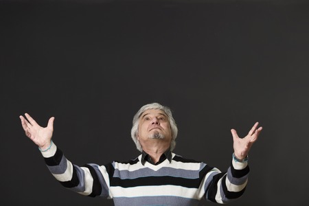 Mature professor man of university or college with two raised arms looking upwards when explaining new material to students or pupils in studio.の写真素材