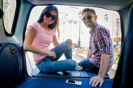 Happy tourist man and woman in sunglasses looking at camera while sitting in car.の写真素材