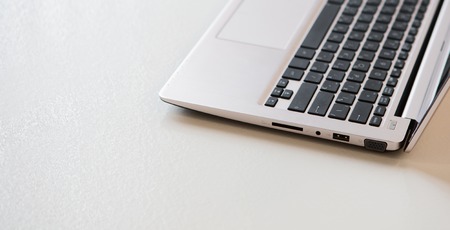 Picture of laptop computer represented on table in office interior. Half of computer with keyboard on table. Laptop computer concept.の写真素材