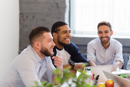 Picture of happy business people working round table in office. People speaking about certain...