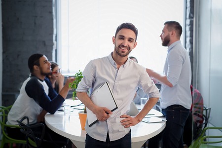 Picture of handsome bearded man in white shirt standing with his hand on hip. Executive businessman...