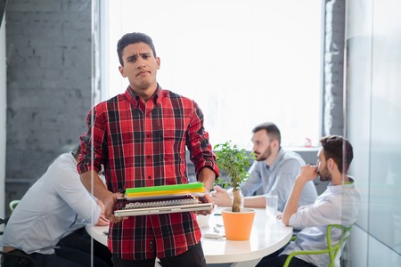 Portrait of serious businessman holding documents of his company, enterprise or firm in office interior while his colleagues or partners having round table.の写真素材