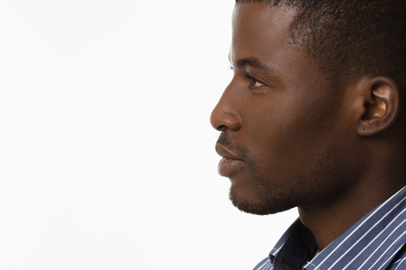 Closeup profile of Afro-American man smiling and looking away while posing over white background in studio.の写真素材
