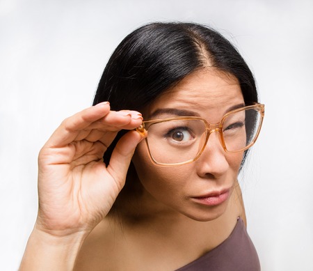 Portrait of beautiful Korean or Asian woman in glasses in studio. Brunette lady posing for photographer over white background.の写真素材