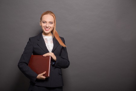 Portrait of beautiful business woman smiling and holding documentation while posing for photographer...