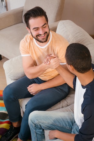 Two best friends men shaking friends while sitting on sofa or couch, Happy friends communicating about business projects.の写真素材