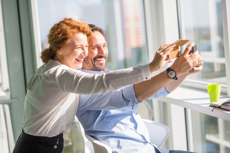 Business people making photos on mobile or smart phone and happy smiling. Workers having break time....