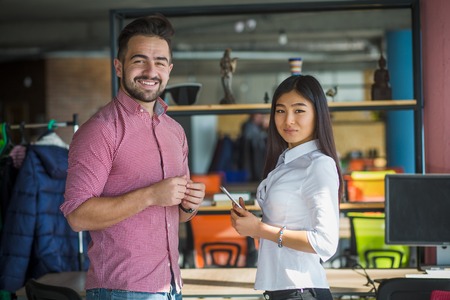 Happy businessman and businesswoman smiling for camera while working in office interior. Colleagues doing business in one company, firm or enterprise.の写真素材