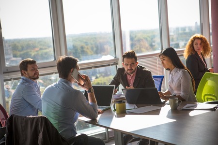 Business people working at round table on laptop computers in board room in office. Businessman...