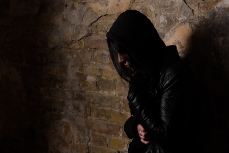 Disease. AIDS concept. Drug addict having depression while posing near brick wall on street. Drug addict having pain.の写真素材