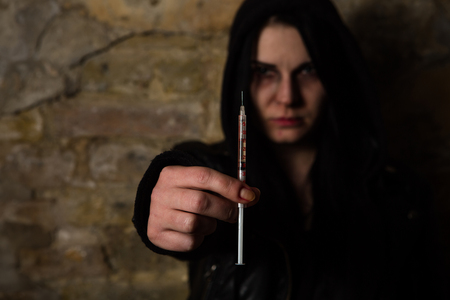 Bad woman. Addict lady with syringe using drugs. Drug addict woman holding syringe with drugs in front of her.の写真素材