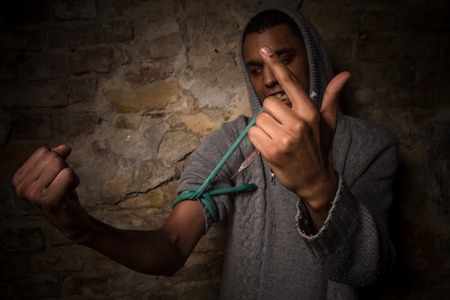 Addict is going to make shot or syringe with substance. Drug addict man on street. Disease, AIDS, HIV concepts.の写真素材