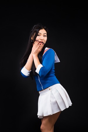 Surprised Asian woman with black hair looking at camera and touching her mouth while expressing different emotions in studio.の写真素材