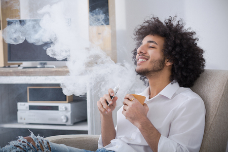 Hipster man smoking at homeの写真素材