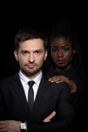 Close up portrait of multi-ethnic couple on black background.