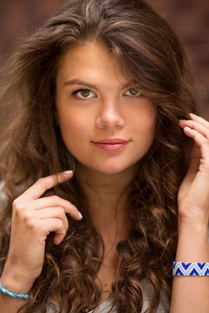Portrait of young woman with long curly hair, showing her hands.