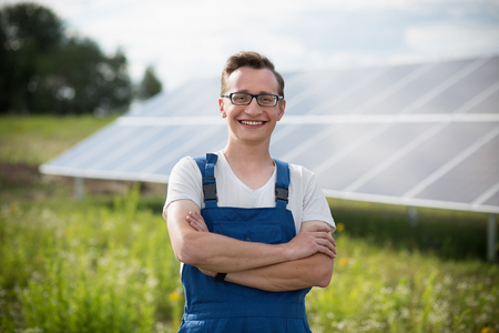 Worker standing in the field with solar with solar panels on backstage.の写真素材