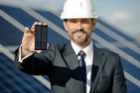 Man in business suit holding photovoltaic detail of solar panel.の写真素材
