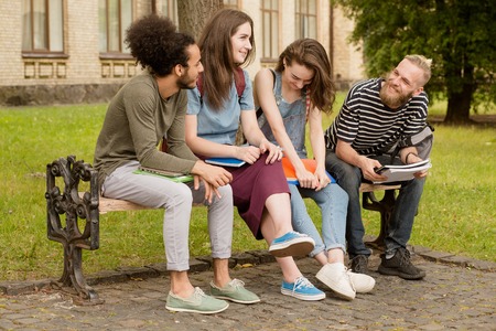 College friends sitting on bench in campus.の写真素材