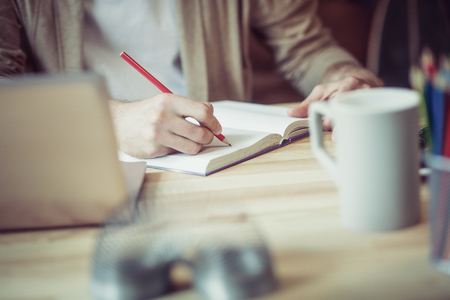 Close up view of man making notes with red pencil.の写真素材