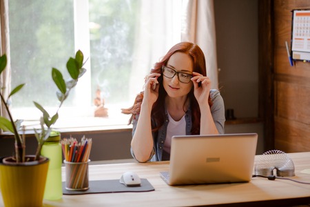 Portrait of freelancer woman talking on phone.