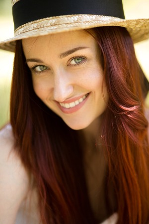 Close up portrait of sexy young lady in straw hat. Foxy woman with blue eyes happily smiling looking at camera. Toned image.の写真素材