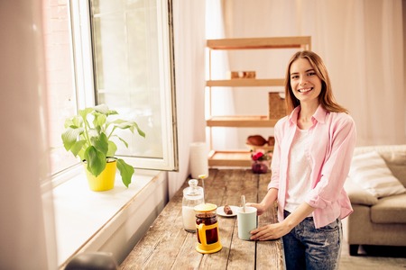 Female having breakfast at home, standing close to window.の写真素材