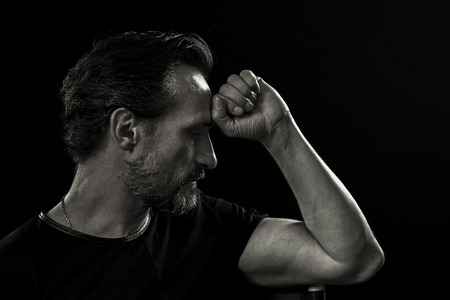 Portrait of a mature man holding fist close to forehead.の写真素材
