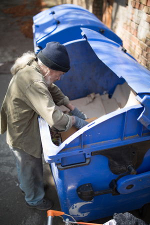 Top view of old homeless male digging in thrash can.の写真素材