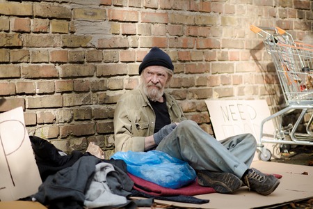 Tramp sitting in the street, his thigns scattered around him.の写真素材