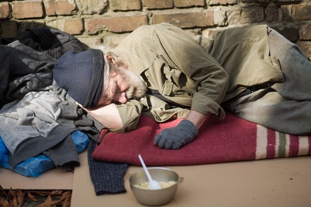 Tired homeless old man sleeping on cardboard in the street.の写真素材