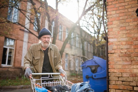 View of homeless old man with cart from supermarket.の写真素材