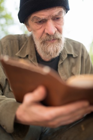 Close up portrait of old beardy man holding book in hands.の写真素材