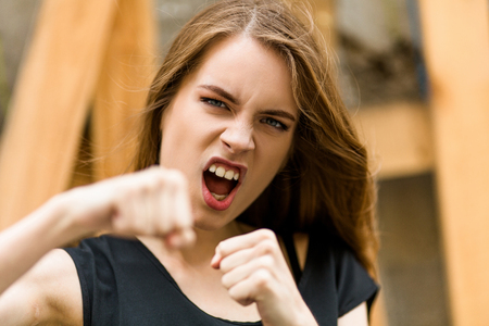Beautiful young female showing fists. Pretty girl showing angry emotion, boxing.の写真素材