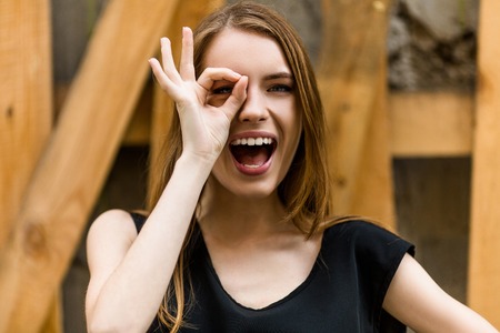 Young and beautiful woman having fun. pretty girl with long hair and clean skin showing OK with fingers.の写真素材