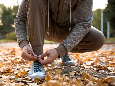 Man lacing his sportive shoes getting ready for jogging in atumn park. Running man outdoors.の写真素材