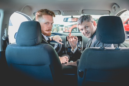 Vehicle dealer and buyer sitting on front seats in new car. Manager showing new car to a young man.の写真素材