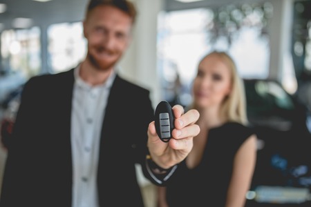 Young couple showing key from new electro car. Man and woman buying new generation electro car....