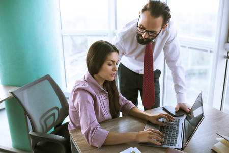 Two coworkers in offfice planning project milestone. Woman typing e-mail. Office concept.の写真素材