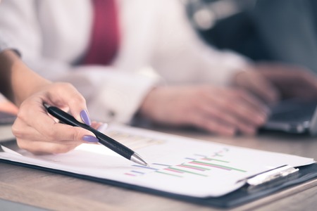 woman manicured hand holding pen and showing data in documents . Office concept.の写真素材