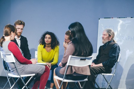 Young girl in yellow sweater retelling her life situations.Group members listening attentively. Toned concept.の写真素材