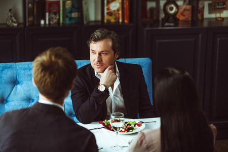 Thre businesspeople sitting at restaurant. Celebrating profitable deal.の写真素材