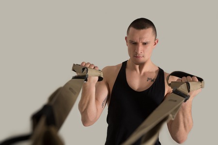 Half length image of strong man at gym. Using equipment.