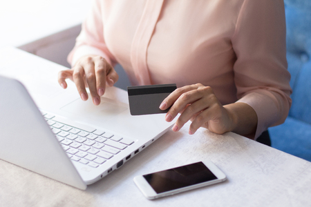 Close up of woman hands typing message on laptop and holding credit card. Transfer money.の写真素材
