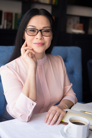 Representative asian businesswoman in glassess sitting at table. Posing on camera.の写真素材