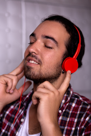 Young man wearing headphones and tightly touching them.の写真素材