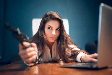 Close portrait of pretty girl lying on office table. Gorgeous female office assistant lying on table with her hands under her cheek with dreamy look on her face.の写真素材